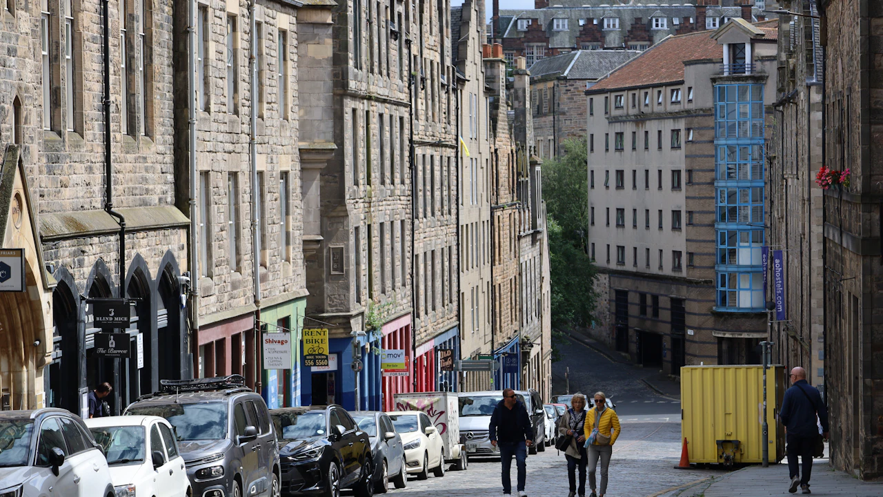 Straße mit steinernen Altbauten und bunten Ladenfronten am Hang