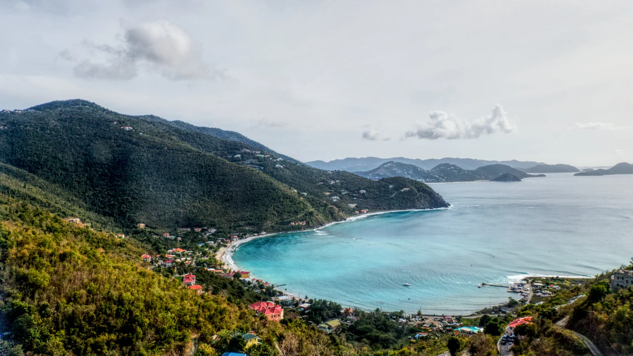 Grüne Hügel um eine geschwungene Bucht mit hellem Strand