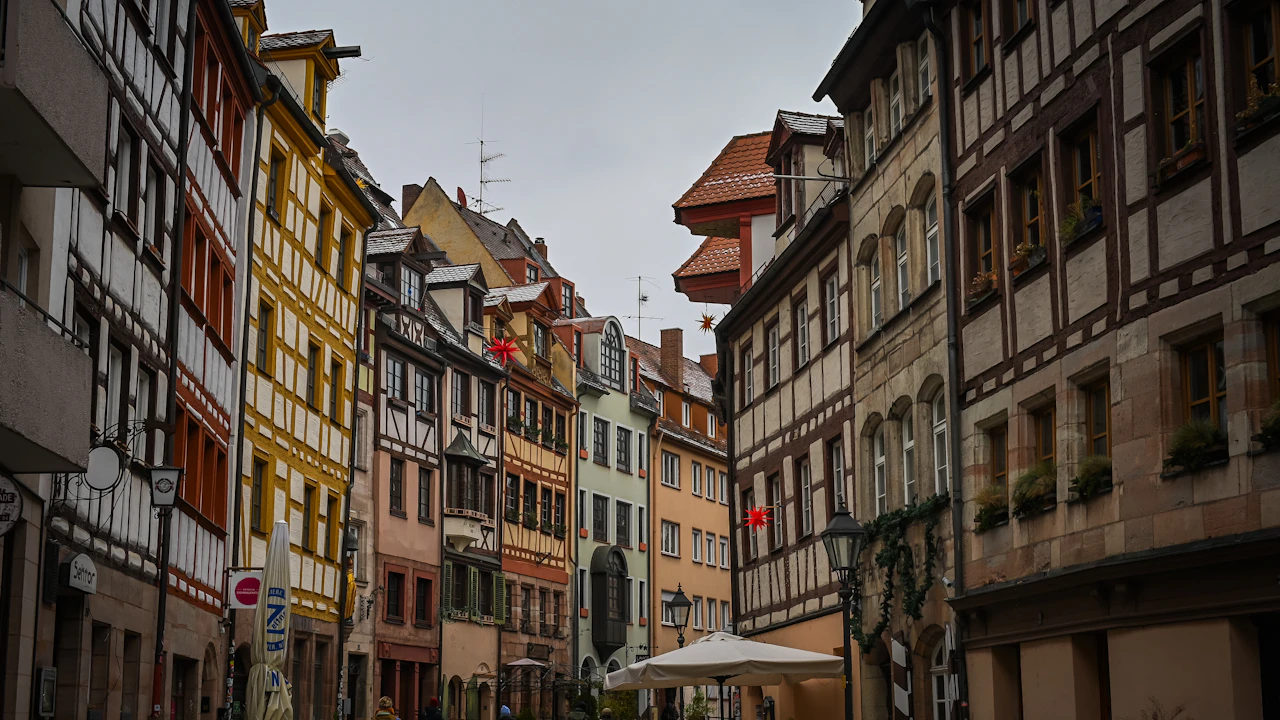 Gasse mit Fachwerkhäusern und Sonnenschirm in einer Altstadt