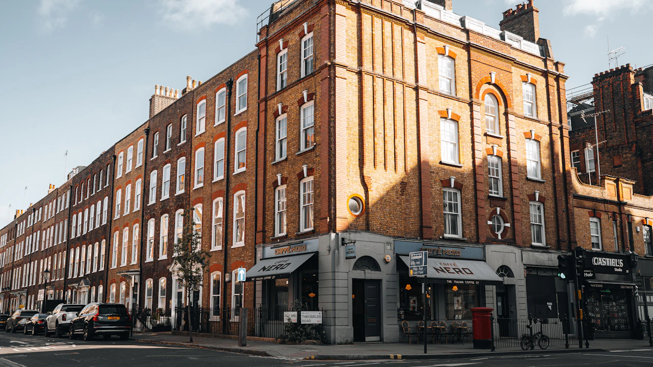Londoner Backstein-Eckhaus mit Straßencafé und roter Briefsäule